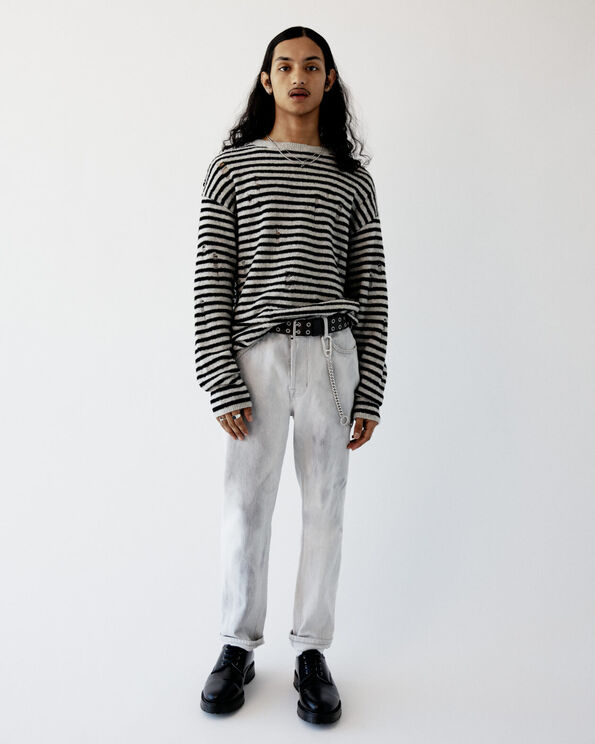 Ace wearing a black and grey striped jumper with jeans and leather boots