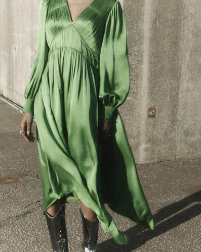 Closeup of a woman wearing a long green dress and metallic leather cowboy boots