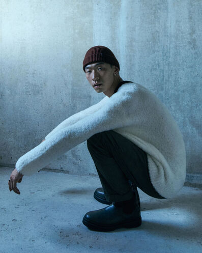 Man wearing an oversized white sweater with black pants and a beanie