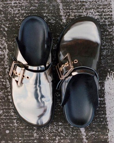 Photograph showing a pair metallic effect sliders mules on the ground.
