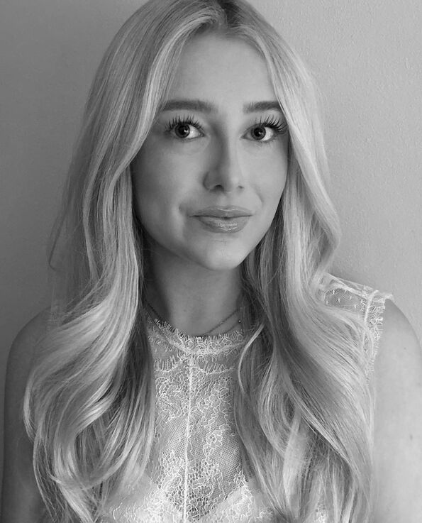 A black and white image of a women with blonde hair and wearing a white blouse with lace