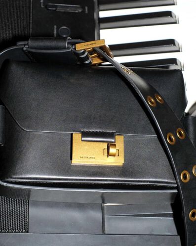 Closeup photograph showing a leather handbag with golden metal details.