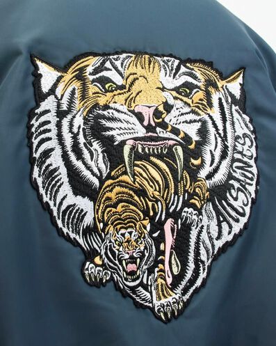 Gros plan sur un patch brodé représentant une tête de tigre avec un plus petit tigre lui sortant de la gueule.