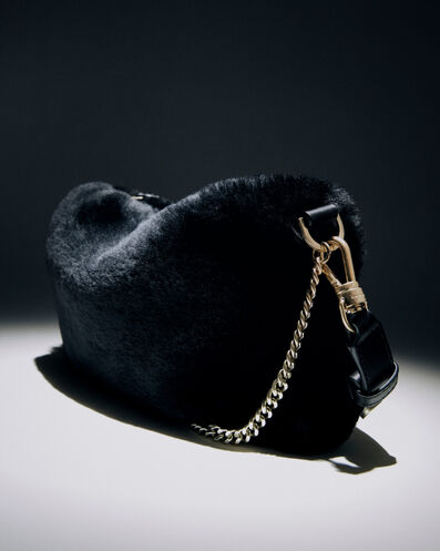 Close up of a black faux fur handbag with gold chain
