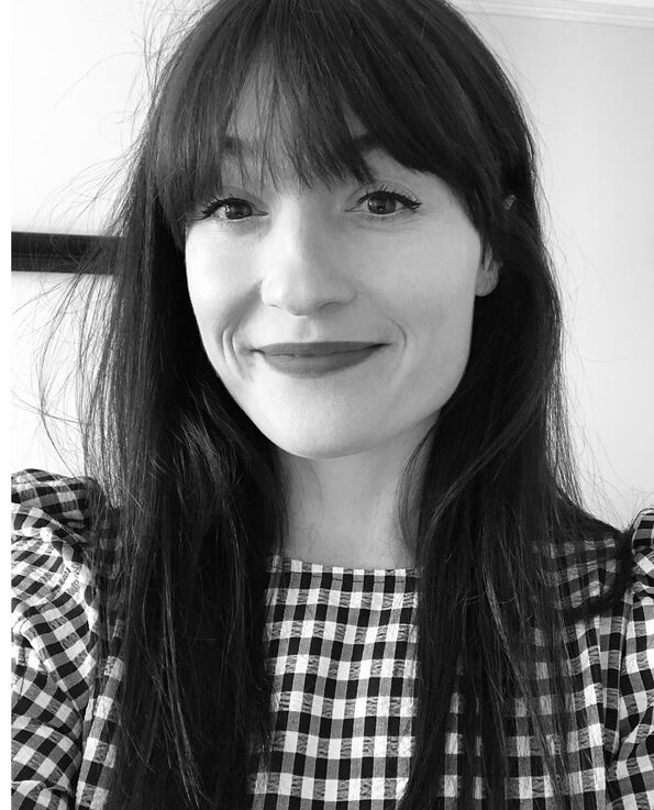A black and white headshot of a women with dark hair wearing a gingham printed top 