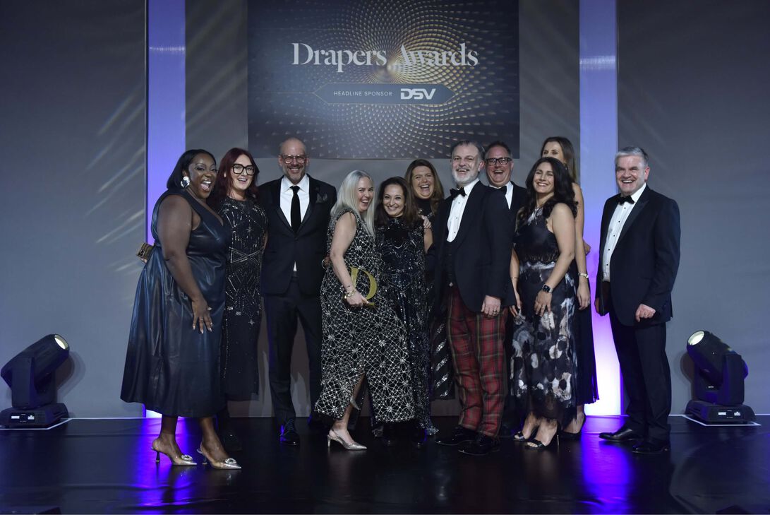 Photograph showing a group of men and women AllSaints employees standing on the Drapers Awards stage.