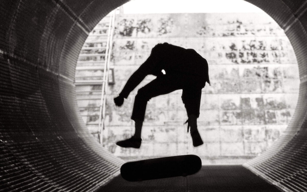 Un homme faisant des figures sur un skate dans un tube métallique.