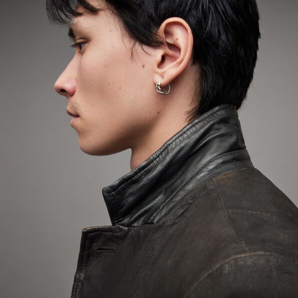 Side profile of a man wear a black leather jacket with the collar up and a silver hoop earring