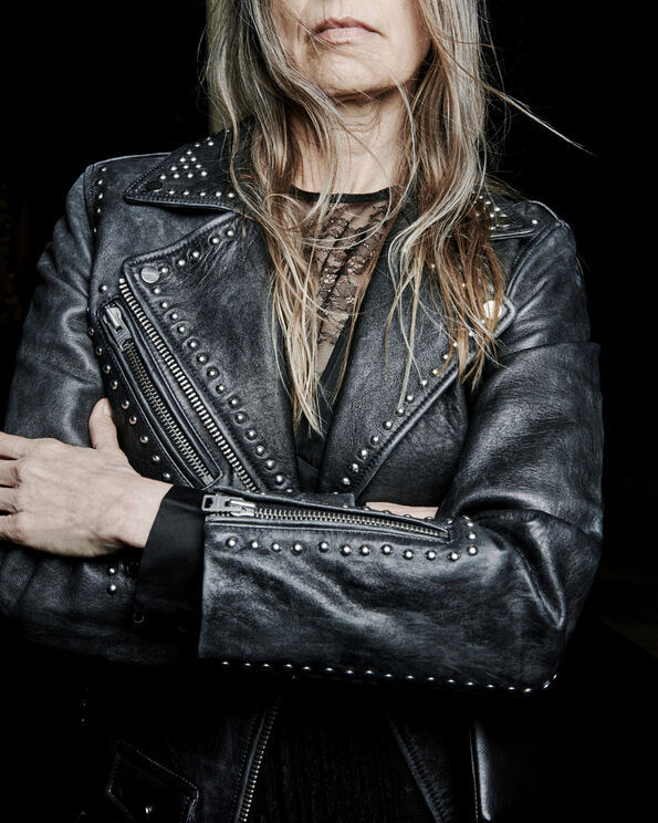 Closeup of an older woman wearing a studded black leather jacket.