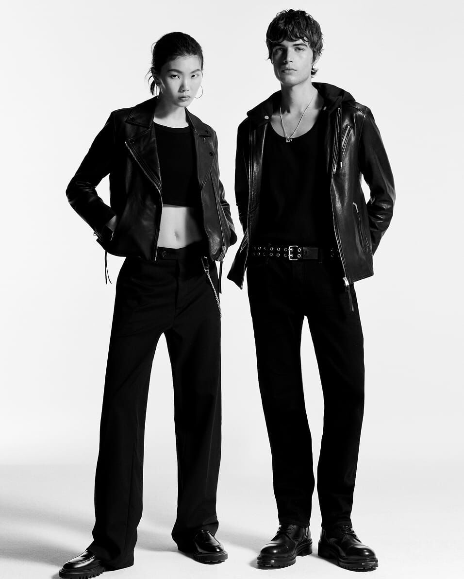 Black and white image of a women and man both wearing black outfits with black leather jackets.