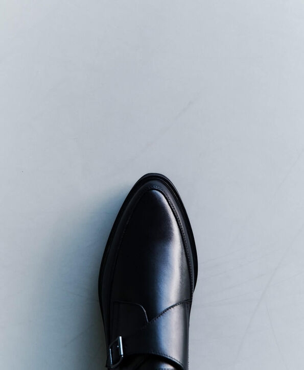 A close up photograph showing a top view of pointed black leather monk shoes.