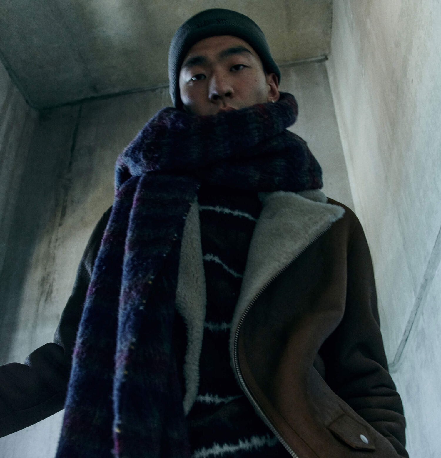 Man wearing a thick blanket scarf with a shearling leather jacket and beanie