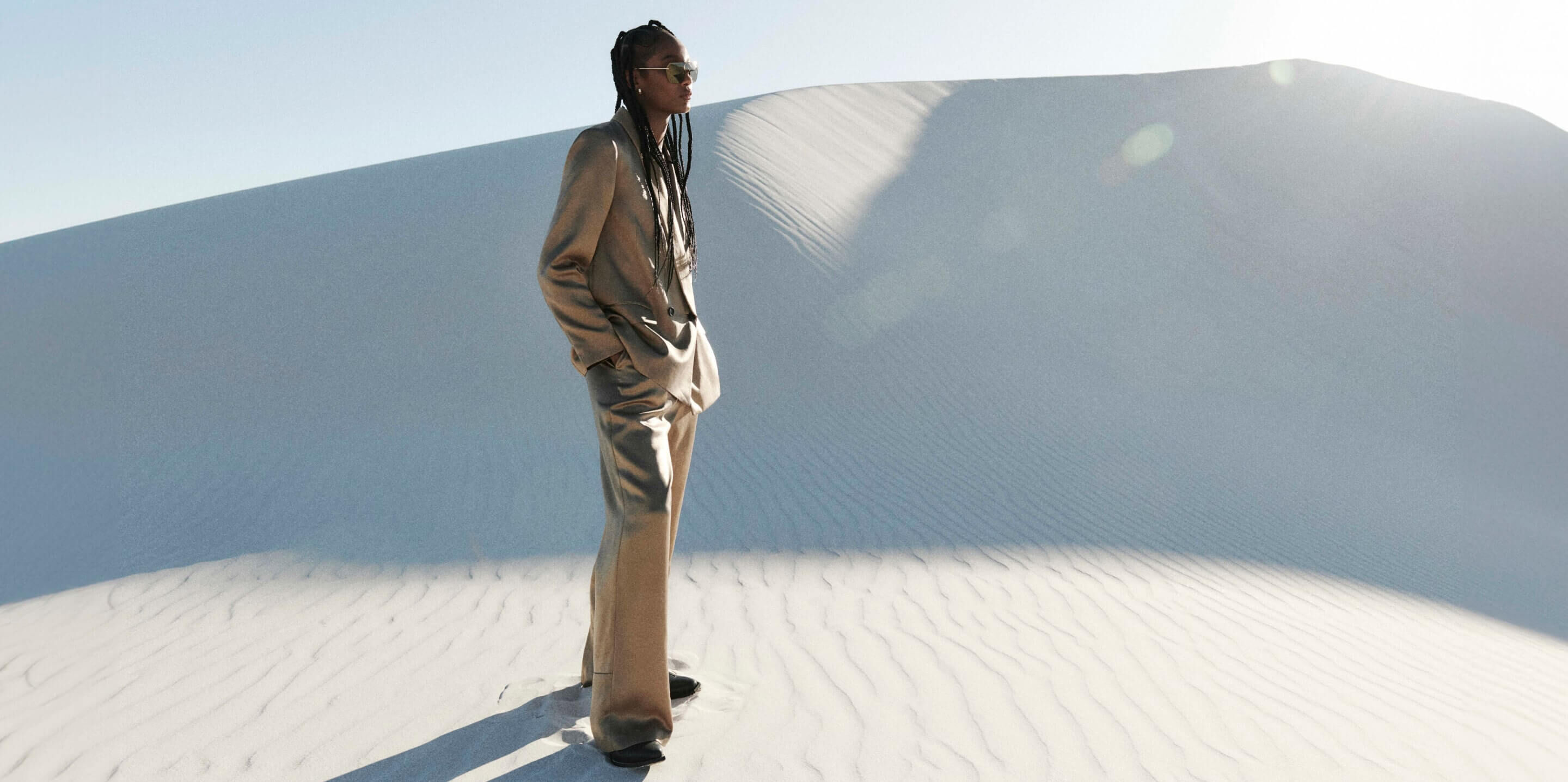 Woman wearing a beige suit jacket and trousers with black leather boots in the desert