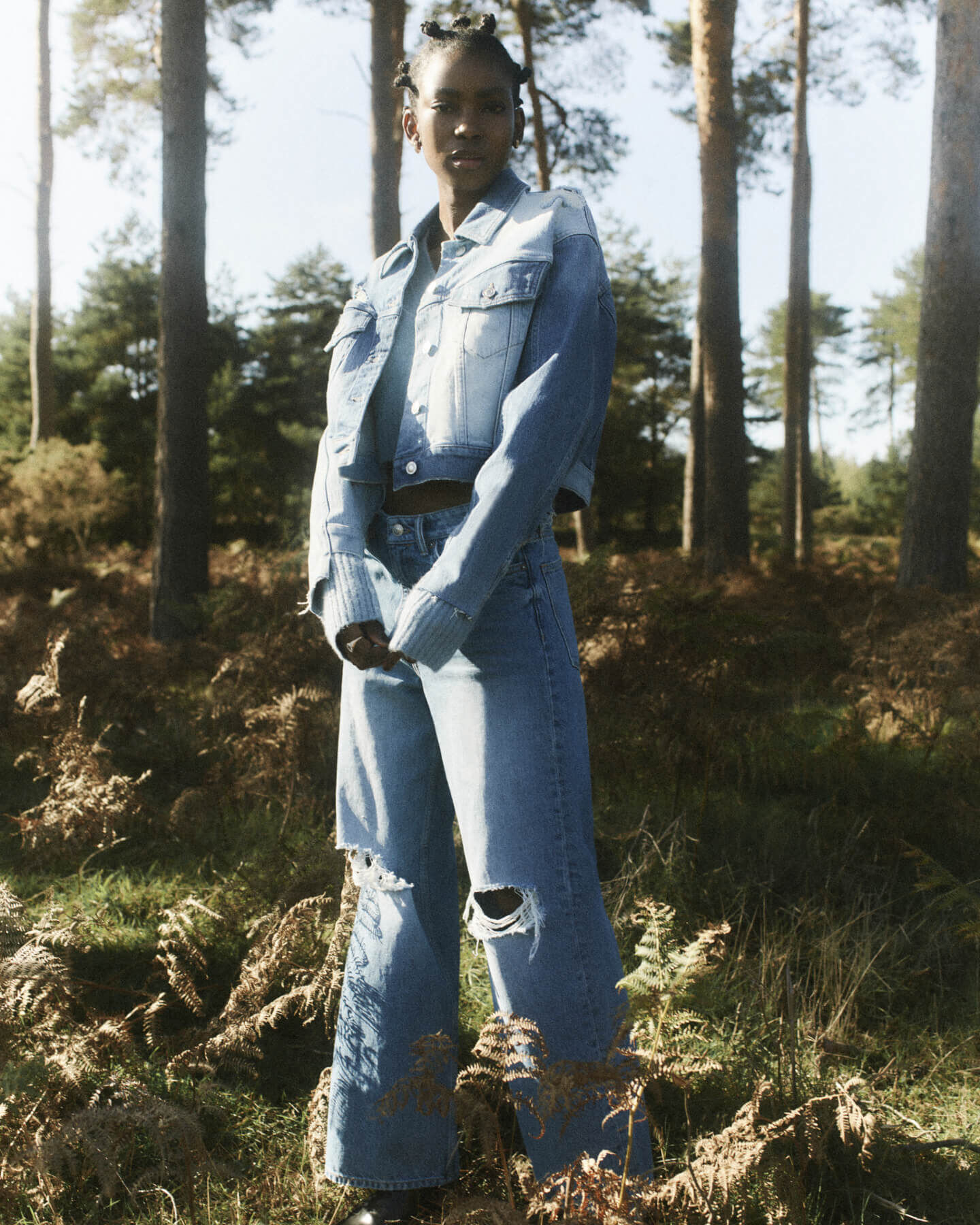 Femme portant une veste en jean et un jean dans un paysage de bruyère.