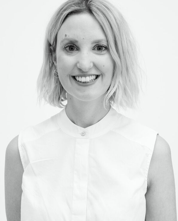 A black and white headshot of a women smiling and wearing a white blouse in front of a white background