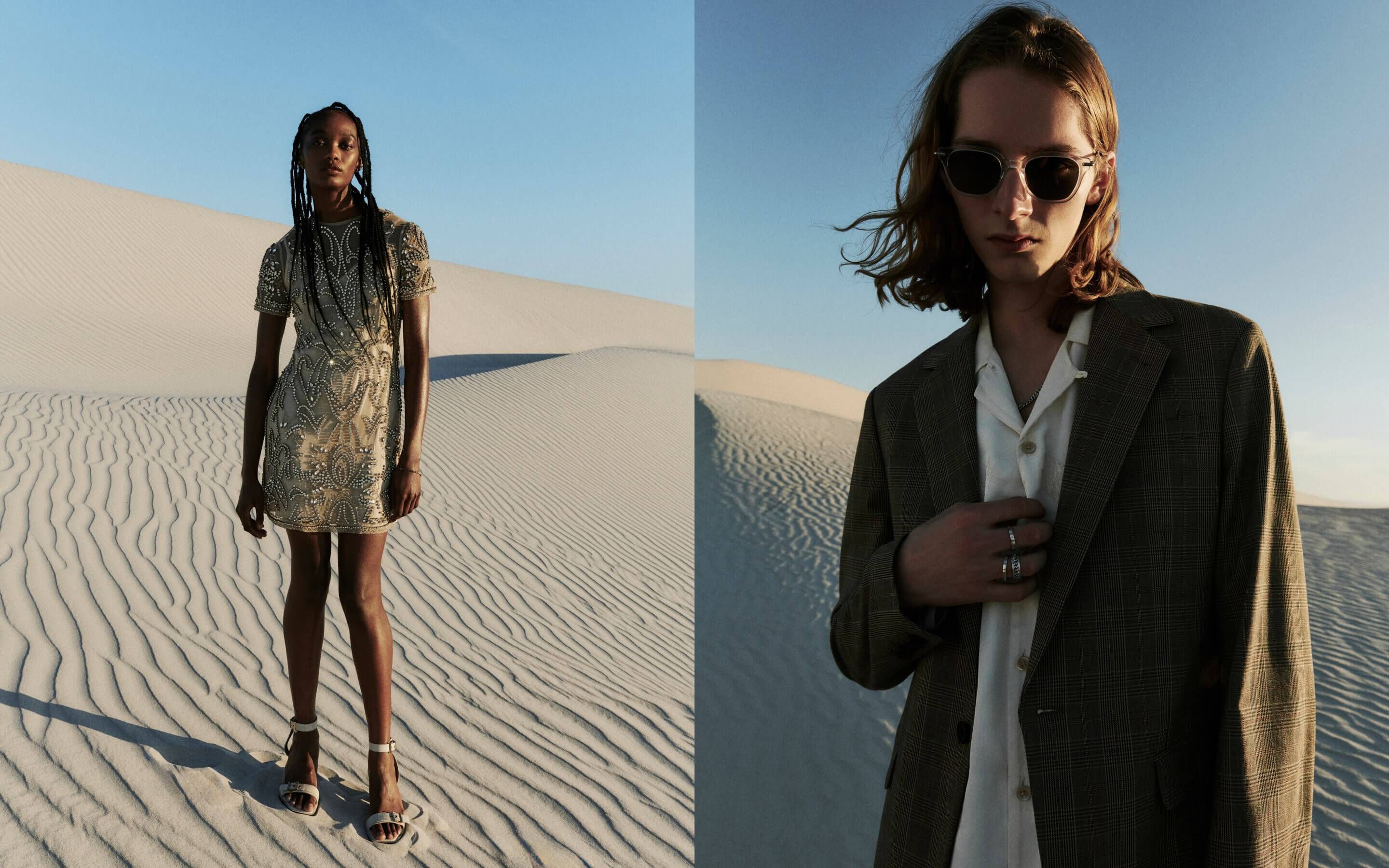 Women wearing a beige beaded dress and high heeled sandals in the desert with a man in a grey checked suit jacket and shirt with sunglasses and silver rings 