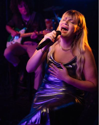 La chanteuse Maddie Zahm chantant dans un micro.