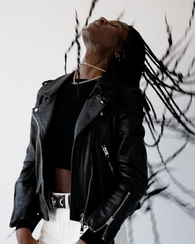Ebun wearing a black leather jacket with white jeans