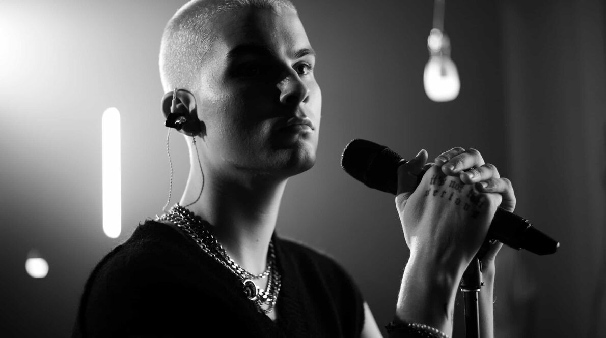 Closeup black and white image of the ASTN singer standing infront of a microphone