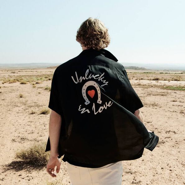 Bild eines Mannes in der Wüste, der ein gemustertes Hemd trägt.