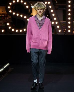 A man wearing an oversized bright pink jumper over a pink and black leopard print shirt catwalking.