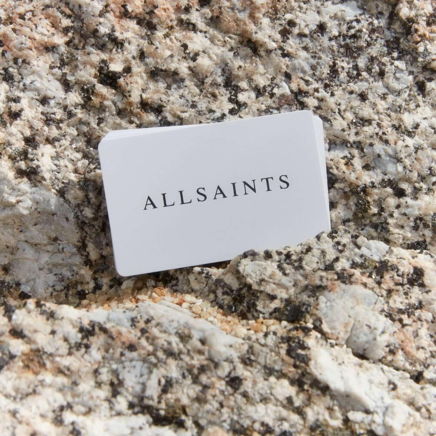 Photograph showing a set of AllSaints GiftCards on a textured stone
