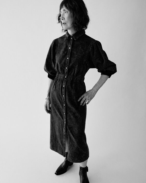 Coco wearing a brown denim dress and black leather boots