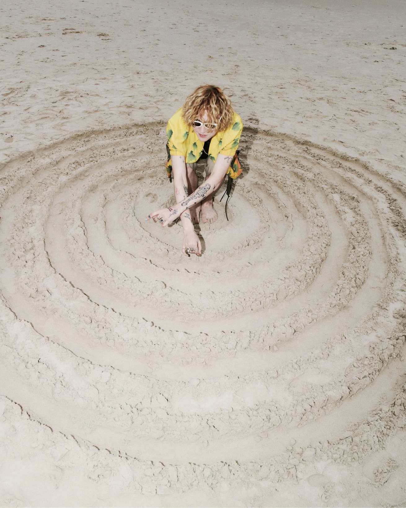 Homme dessinant de grands cercles dans le sable.